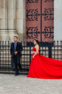 Woman with umbrella against red wall