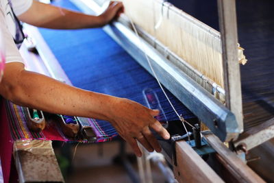 Midsection of person weaving textile in loom