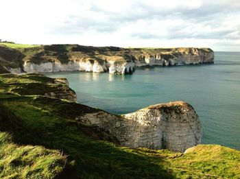 Scenic view of cliff by sea against sky