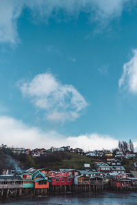 Buildings by river against sky