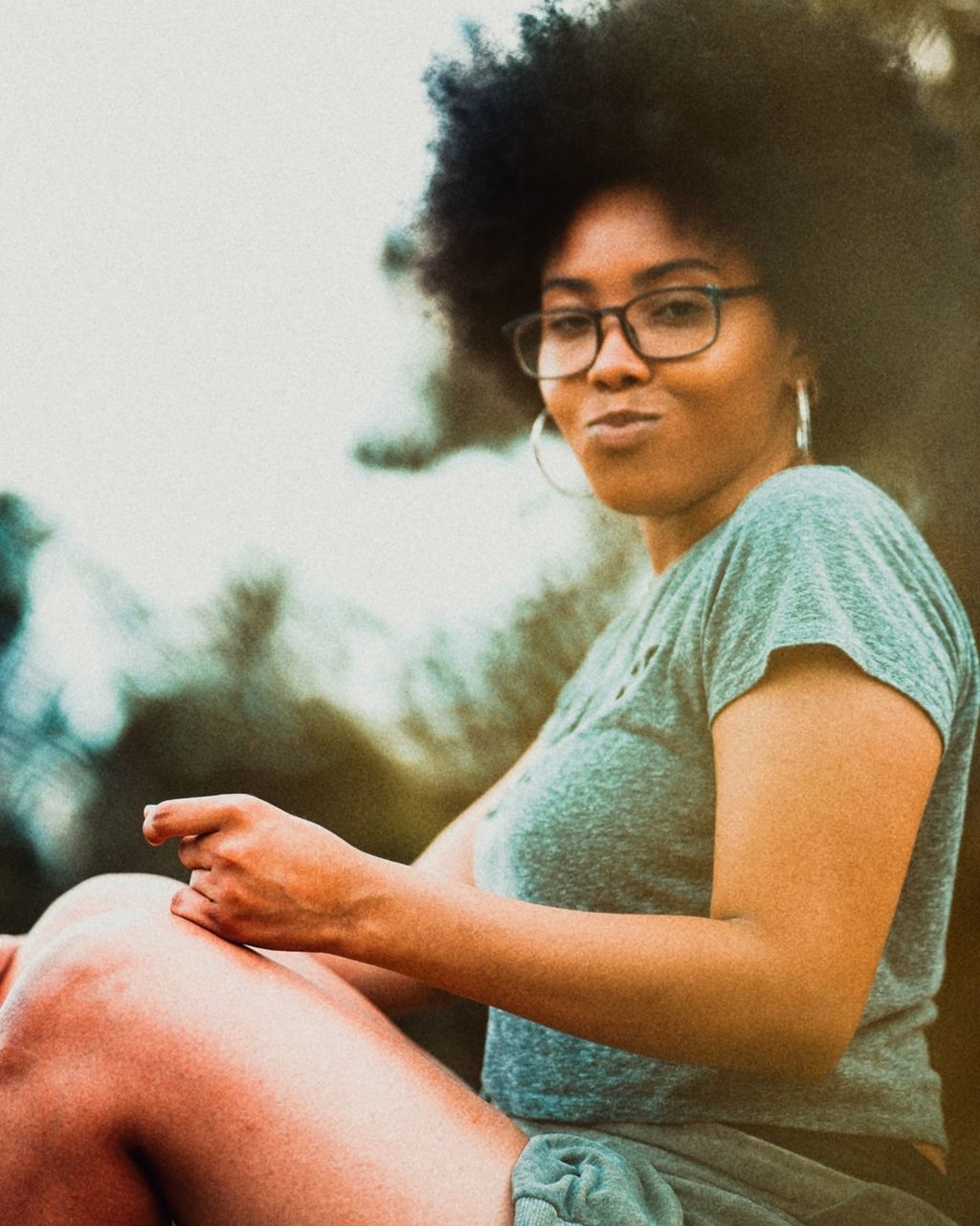 one person, sitting, eyeglasses, glasses, three quarter length, casual clothing, real people, young adult, looking at camera, focus on foreground, portrait, lifestyles, leisure activity, indoors, day, waist up, smiling, front view, arms crossed, hairstyle