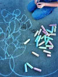 Midsection of child playing with chalk on street