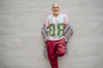 Portrait of mature gay man standing against wall