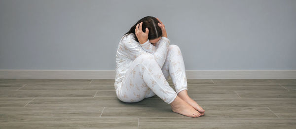Portrait of young woman sitting on hardwood floor