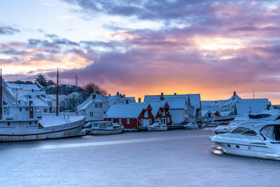 Boats moored in harbor at sunset