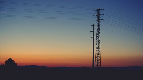 Low angle view of silhouette electricity pylon against sunset sky