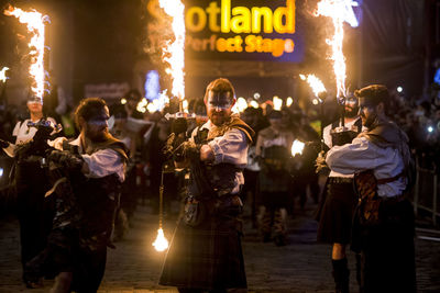 Group of people at illuminated street in city at night