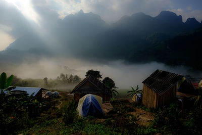 Tent on field by houses against sky