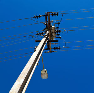 Low angle view of electricity pylon against clear blue sky