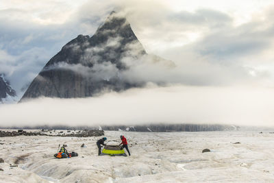 People on snowcapped mountain against sky