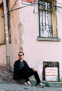 Full length of man sitting on footpath