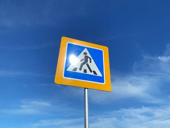 Low angle view of road sign against blue sky