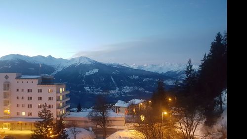 Snow covered houses and mountains against sky at night