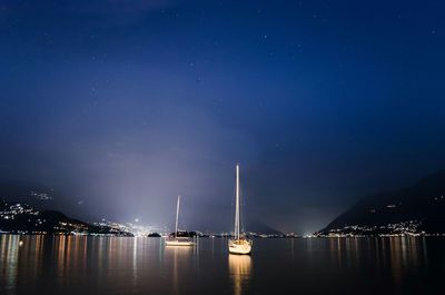 Sailboats sailing in river against sky at night