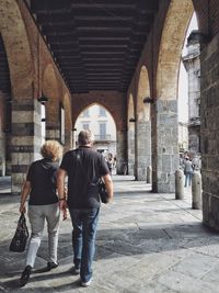 Rear view of man and woman walking below bridge