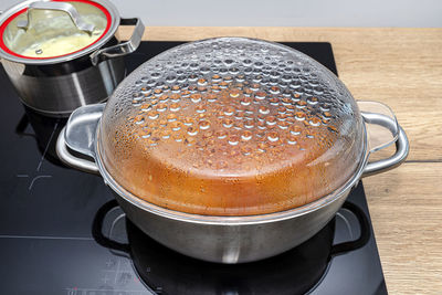 Steel pots with a cooking dish on an induction cooker built into the kitchen worktop on the cabinets