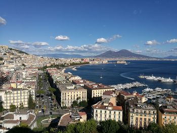 Aerial view of town by sea against blue sky