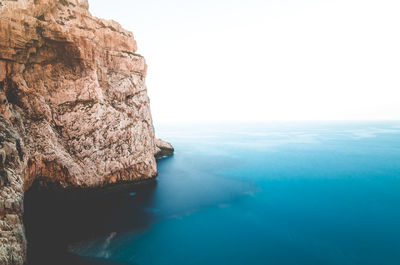 Rock formations by sea against clear sky