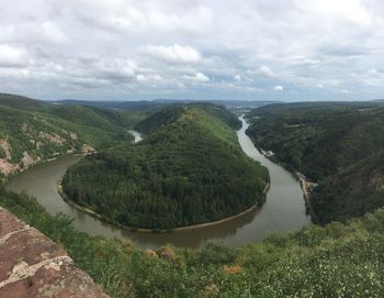 Scenic view of river amidst green landscape against sky