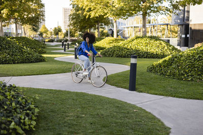 Smiling woman with bicycle on footpath in park