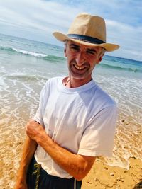 Portrait of mature man wearing hat while standing at beach