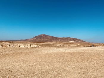 Scenic view of desert against clear blue sky