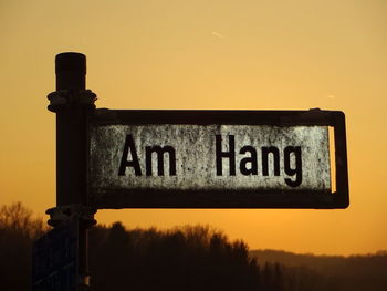 Low angle view of information sign against sky during sunset