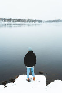 Rear view of person standing in lake during winter