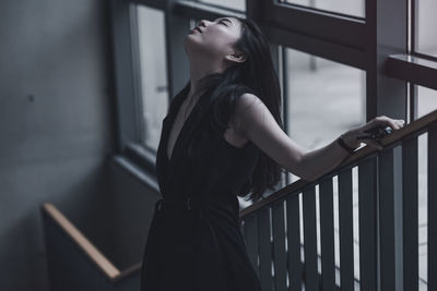 Side view of woman looking away while standing on railing