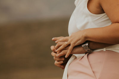 Cropped hands of man embracing woman