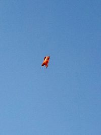 Low angle view of airplane flying against clear blue sky