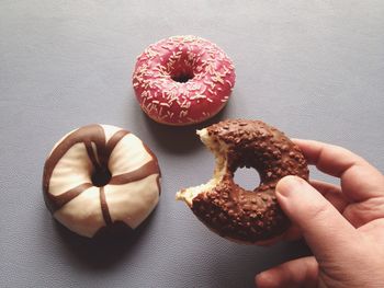 Close-up of cropped hand holding donut on table
