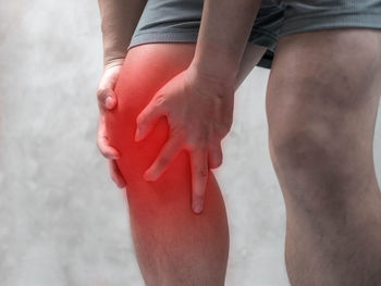 Digital composite image of man holding knee in pain