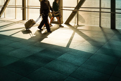 Low section of people walking with trolley luggage at the airport