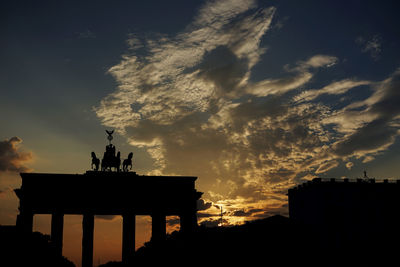 Silhouette of building against cloudy sky during sunset