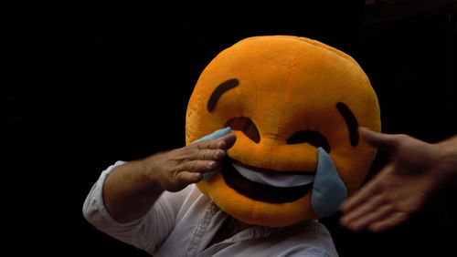 Close-up of man holding camera against black background