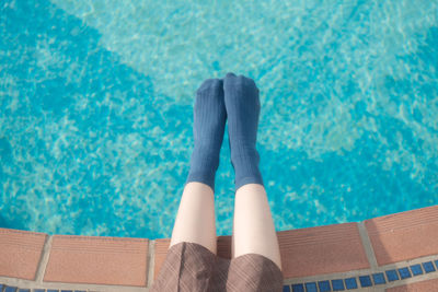 Low section of woman relaxing in swimming pool