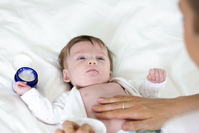 Cropped hand of woman applying cream on son belly