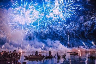 Firework display over canal in city at night