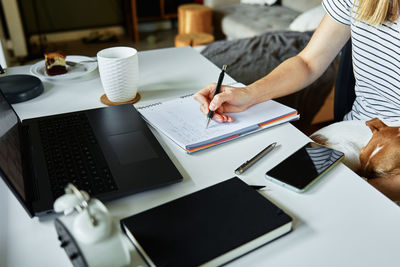 Woman working at home office, use laptop and hold dog on hands