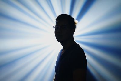 Young man standing against light beams