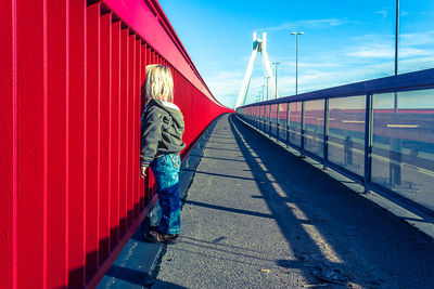 Rear view of man standing by suspension bridge against sky
