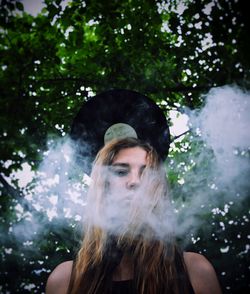 Close-up of young woman against trees