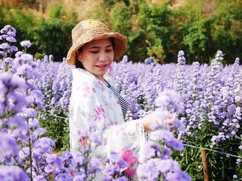 Beautiful woman standing by purple flowering plants