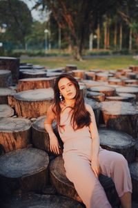 Portrait of young woman sitting on tree stump