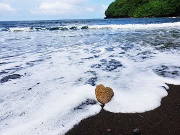 Pebbles on shore at beach against sky