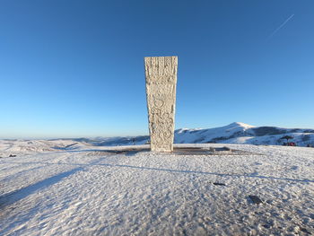 Built structure on snow covered land against clear blue sky