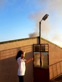 Side view of teenage girl standing by wall