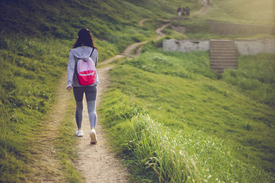 Rear view of woman walking on footpath