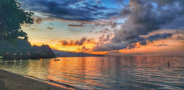 Scenic view of sea against dramatic sky during sunset